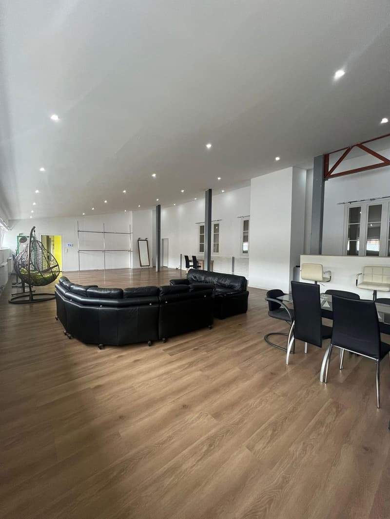 large open space, hardwood floor, L-shaped sofa, dining table, white chairs, metal ceiling