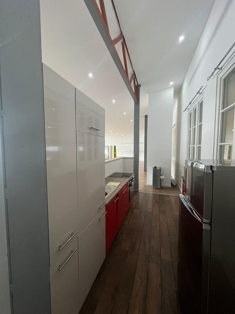 modern white cabinets, red cabinets, wooden floor, large stainless steel refrigerator, open kitchen area
