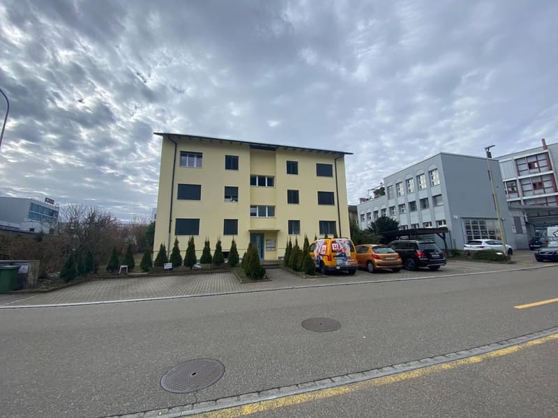 A yellow building with multiple windows and multiple vehicles parked in front