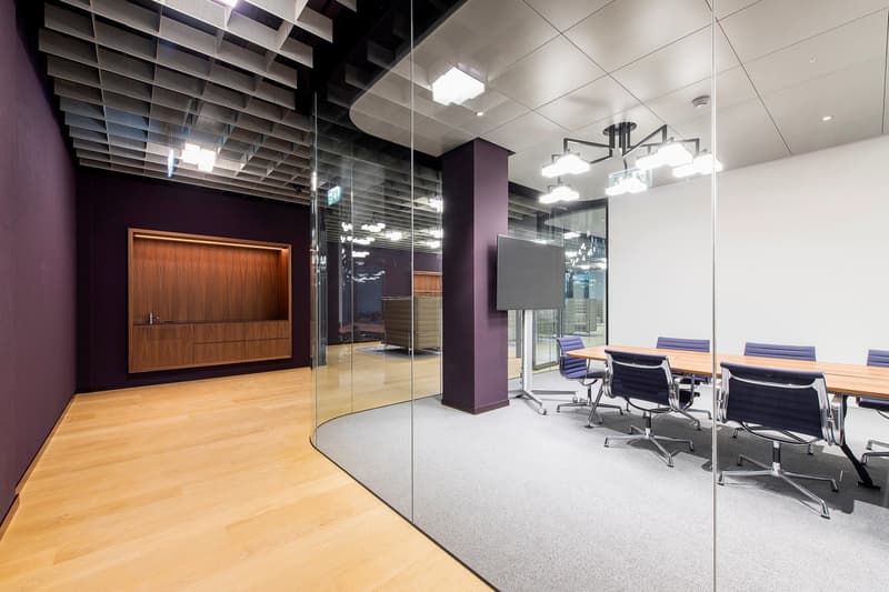 Office meeting room with glass walls, wooden floor, long wooden table, purple walls, modern office chairs, large screen, wooden cabinet