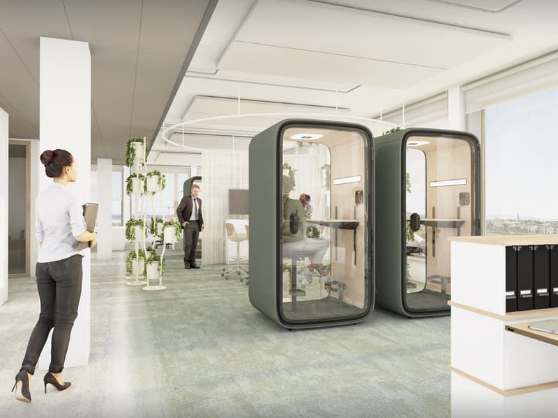 Modern open-plan office space with glass-enclosed meeting pods, hanging plants, and a view of the city skyline.