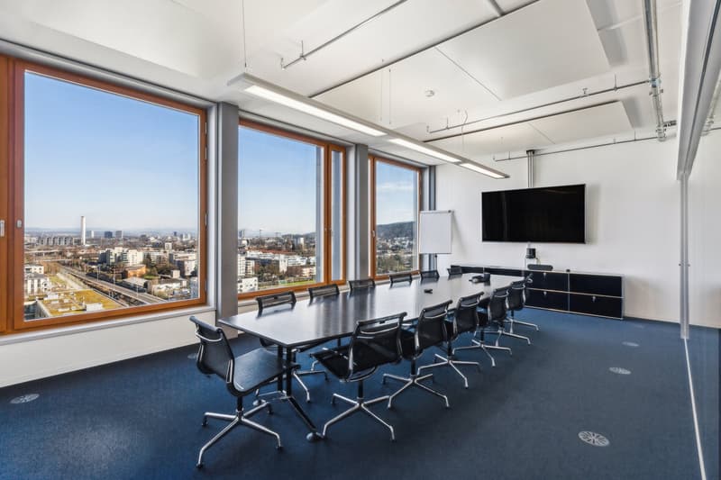 Conference room with large windows, long table, black chairs, whiteboard, TV