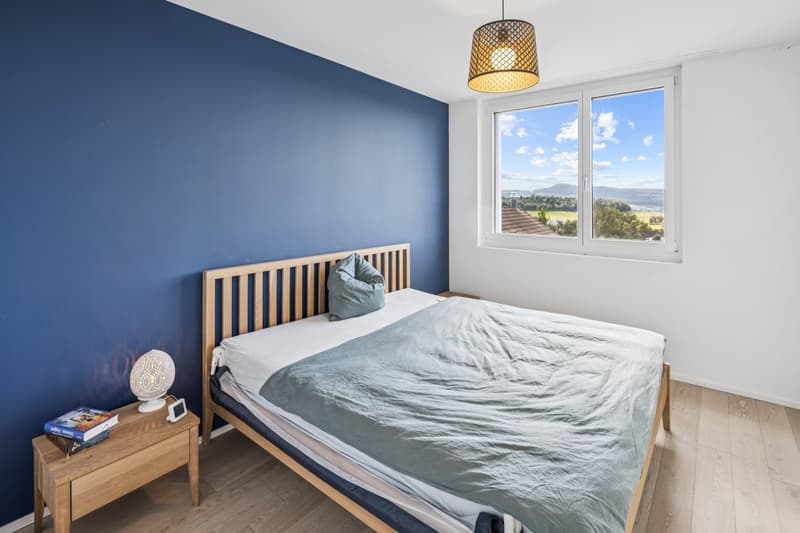 blue wall, wooden bed, bedside tables, large window, city view