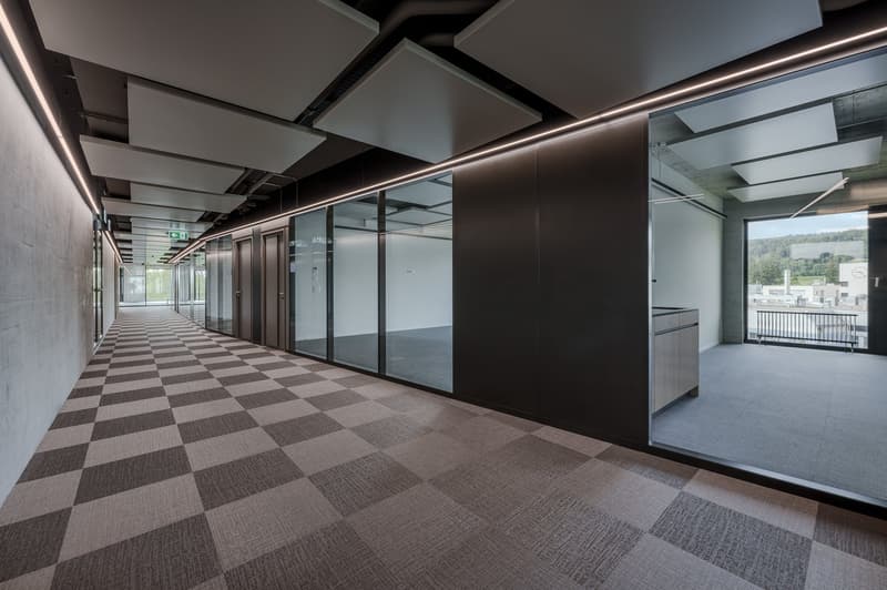 Empty hallway with checkered floor, glass walls, and doors, and a balcony with a view