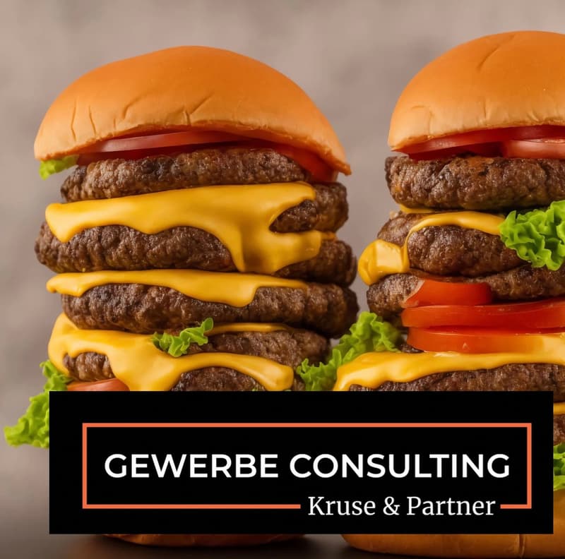 Two hamburgers stacked on top of each other, with multiple layers of beef patties, cheese, lettuce, and tomato.