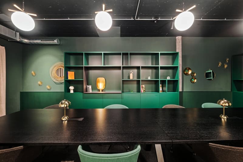 conference room with green shelves, hanging lights, black table, chairs, lamps, wall decorations