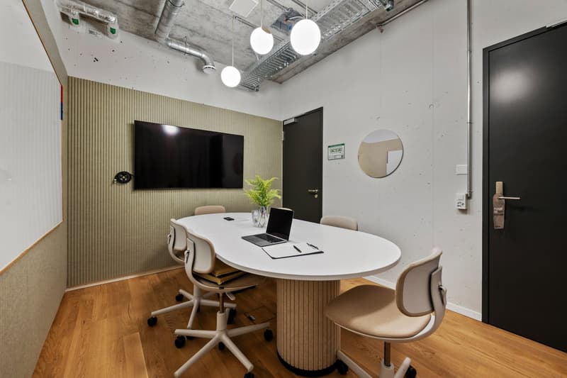 Conference room, oval table, modern chairs, laptop on a desk, mirror, TV