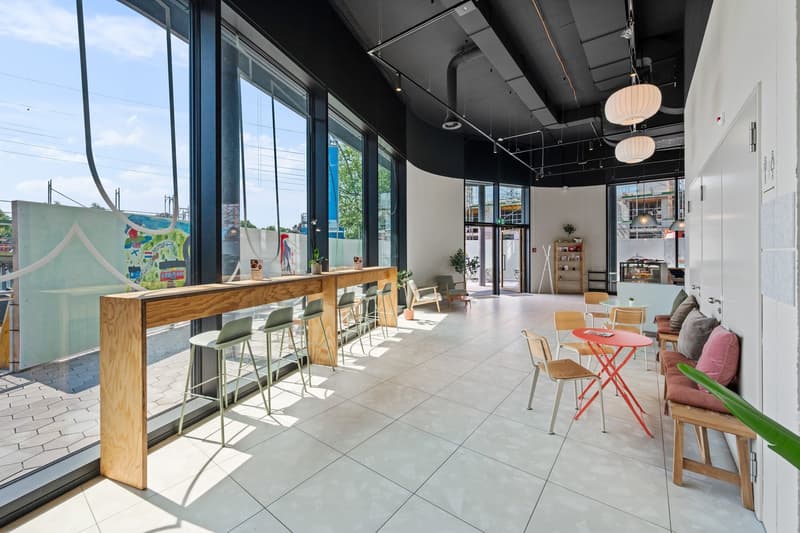 Wooden counter with bar stools, chairs and tables, large windows, white flooring, modern fixtures