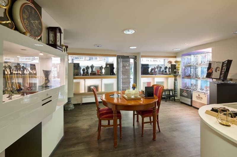 wood floor, round table with two chairs, glass showcases, vintage clocks, wooden pedestal