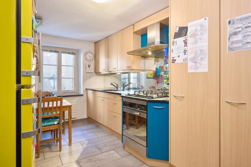 modern kitchen with wooden cabinets, gas stove, oven, blue accents, dining table, clock on wall
