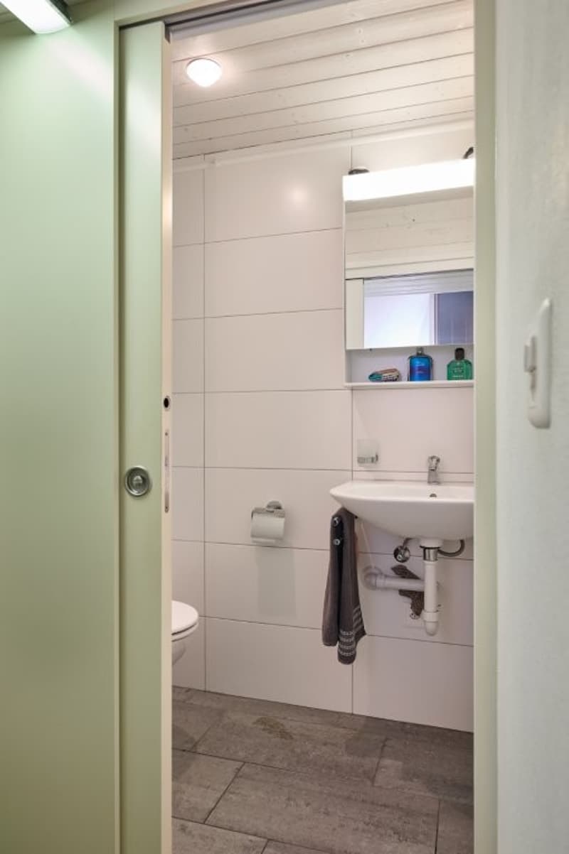 compact bathroom with toilet, sink, and mirror above sink