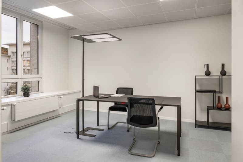 Minimalist room with a desk, chairs, and a ceiling lamp, offering a view of the exterior