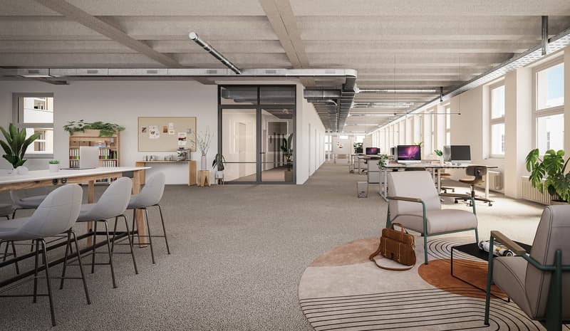 Open concept office space with exposed ceiling beams, large windows, workstations with computers, a kitchen/dining area with bar stools, and various plants and decor elements throughout the space.
