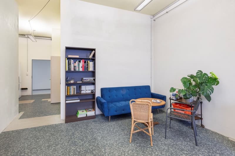 empty room with a blue couch, a bookshelf, a small table, and a plant