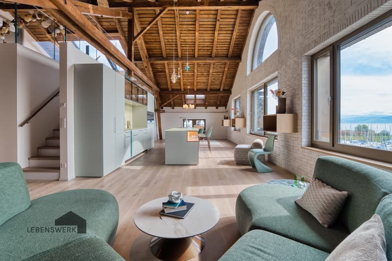 Die gemütliche Lounge lädt zum Ankommen, Lesen oder einem Glas Wein ein, während die Sonne durch die grossen Fenster den Raum in warmes Licht taucht