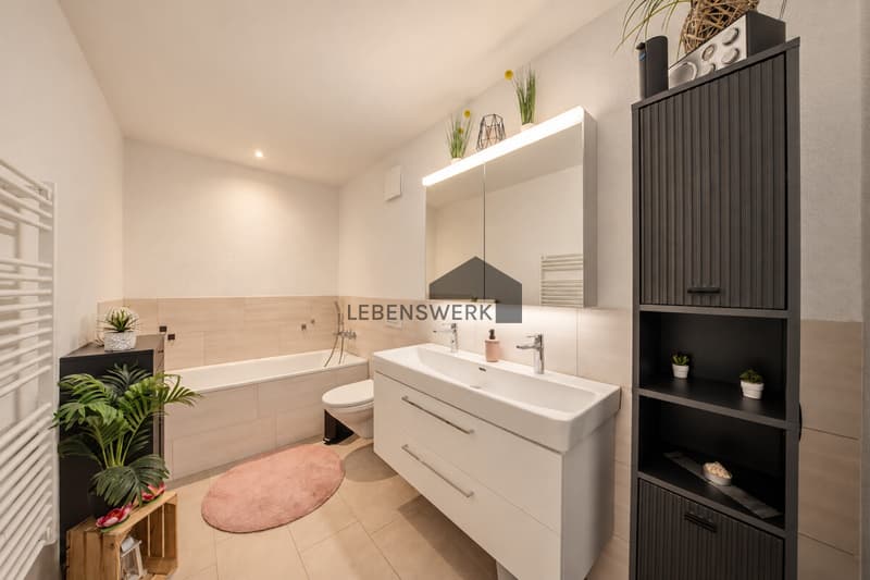 Einladendes Badezimmer mit Badewanne und grosszügigem Waschtisch für entspannte Alltagsmomente.