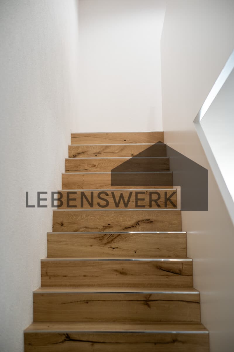 Die Treppe in warmer Holzoptik verbindet die drei Wohnebenen und setzt einen wohnlichen Akzent.