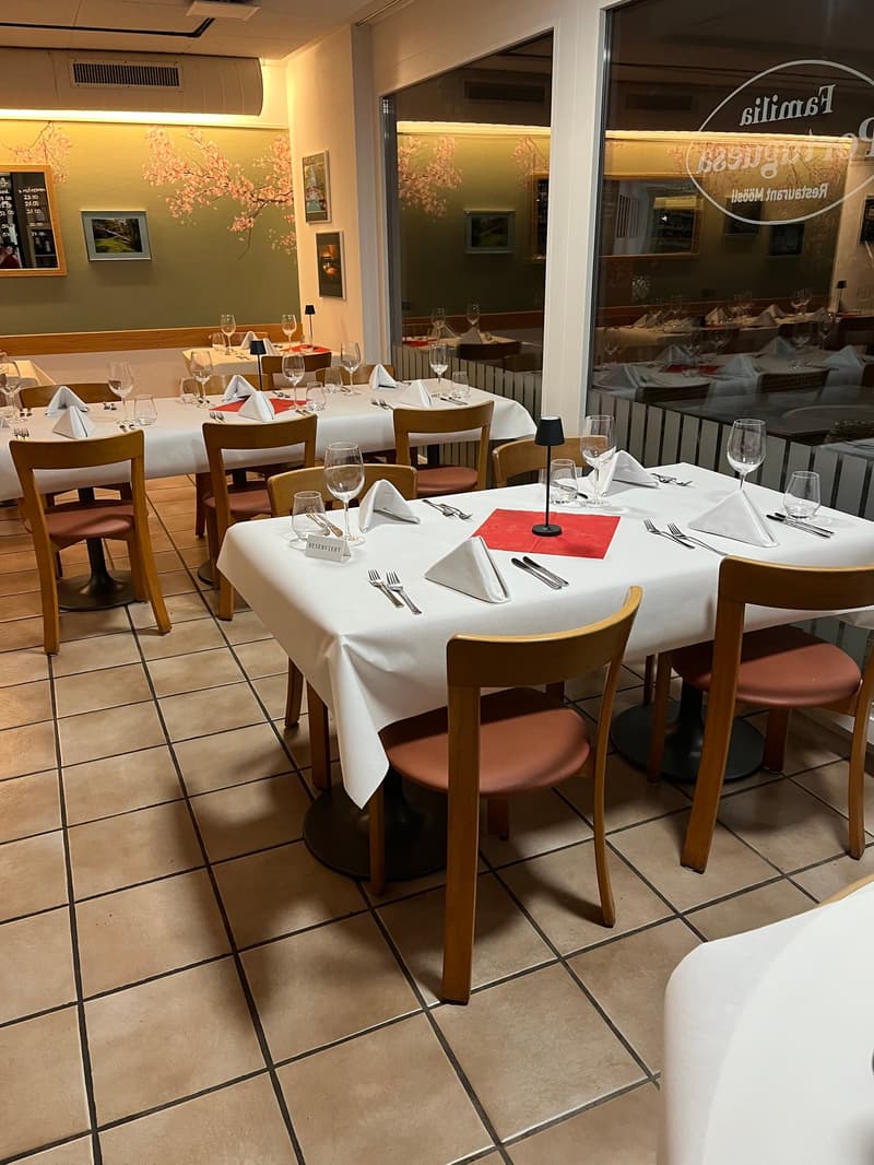 Modern dining tables, chairs, and wooden floors, tables covered with white cloths, silver utensils, and red name cards.