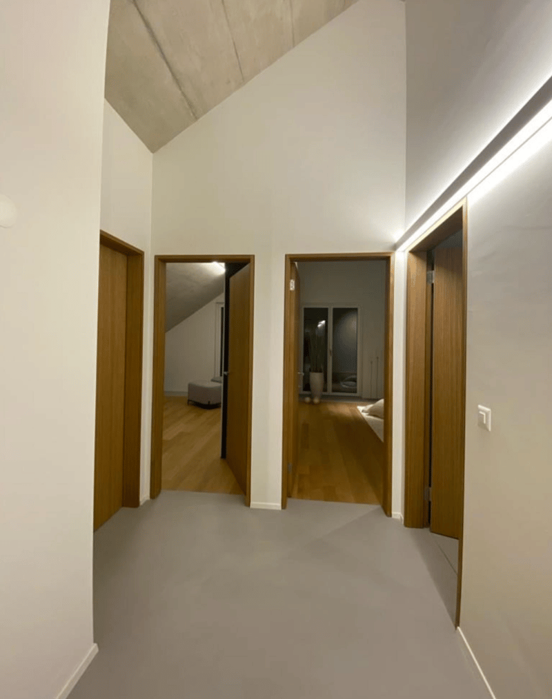 Corridor with wooden doors, wooden floor, white walls, natural lighting
