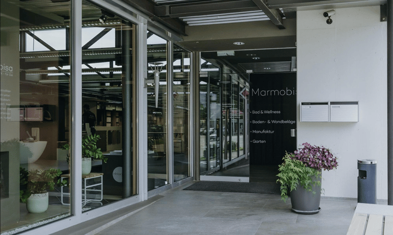 entrance to a showroom, glass wall, glass door, potted plants, surveillance camera, mail boxes