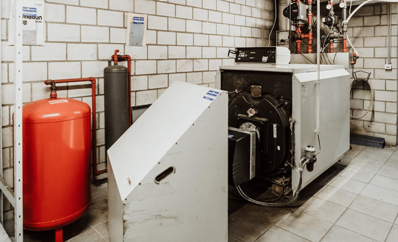 Boiler room with white tiled floor, red and gray gas tanks, a white appliance with black top