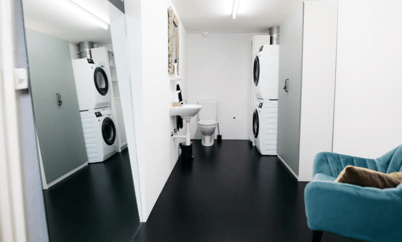 2 washing machines, sink, toilet, chair, mirror, cabinets