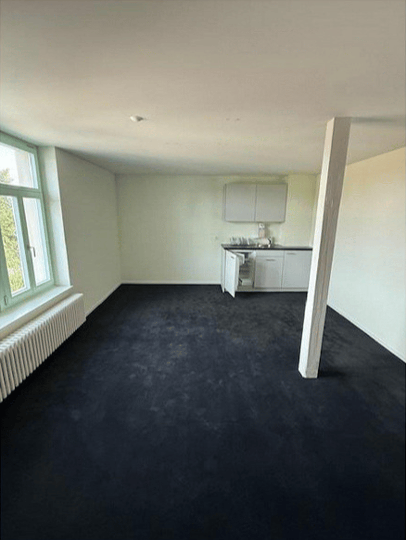empty room with a radiator, an open refrigerator, built-in cupboards, and a window