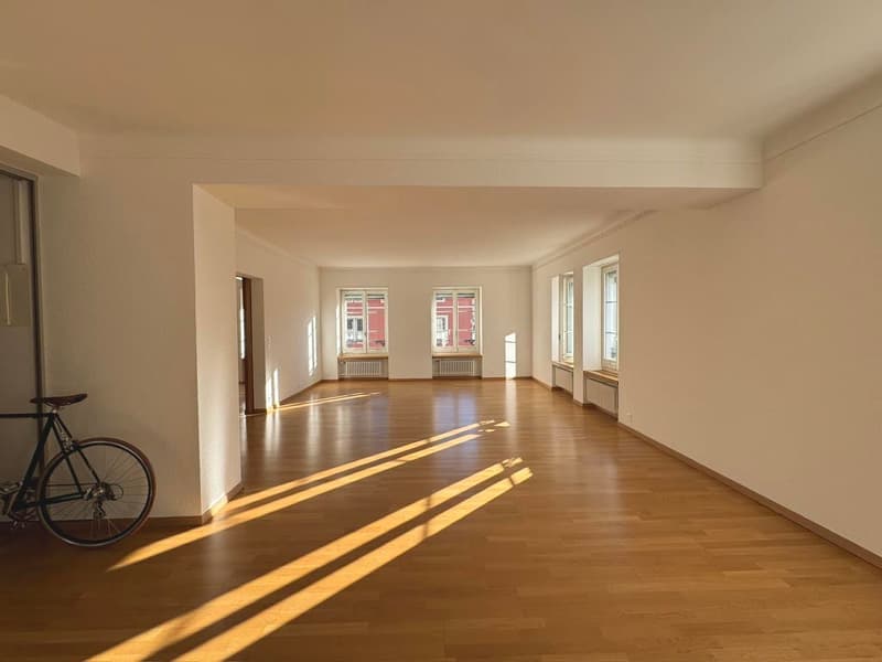 large room, wooden floors, white walls, large windows, sunlight