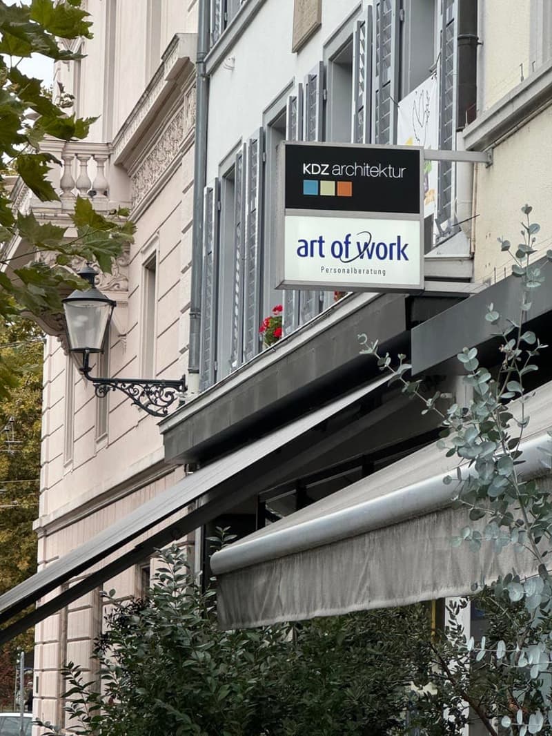 White building with awnings and lamp, signage for Kdz architektur, art of work.