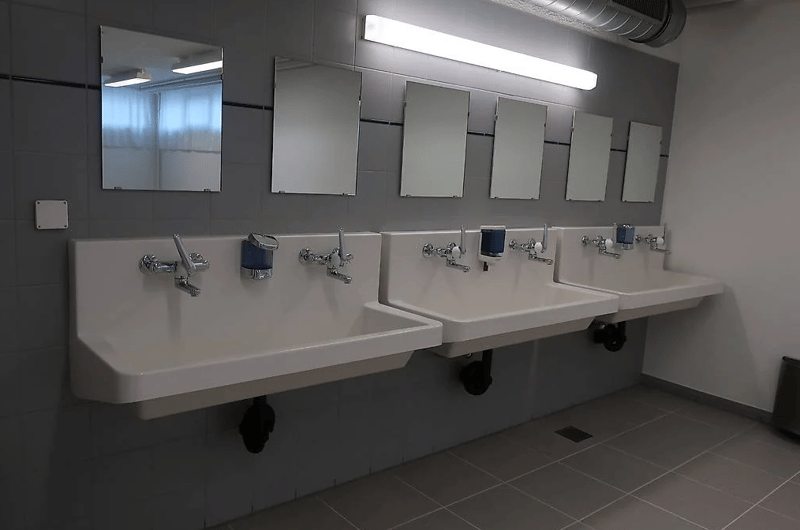 3 wash basins, 4 mirrors, grey tiled floor, white tiled walls, lighting and dispensers