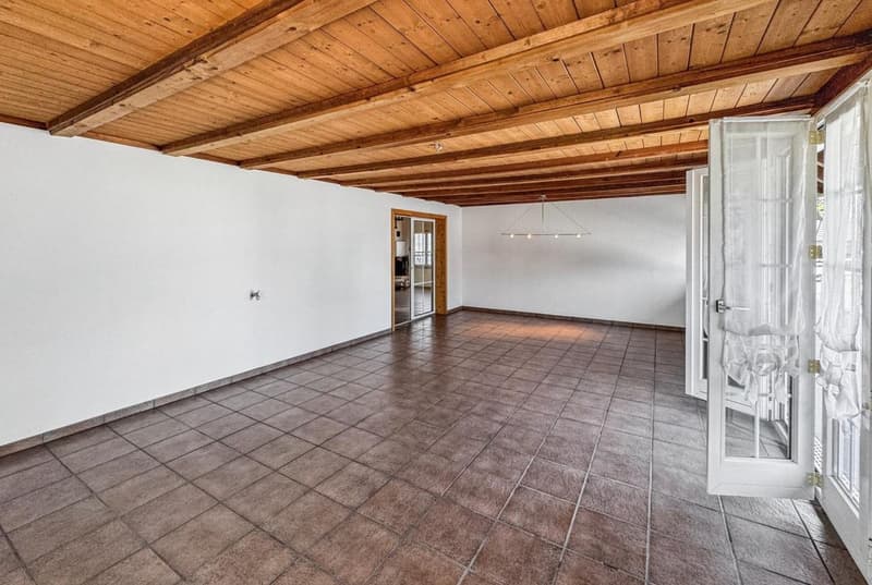 Open room with wooden ceiling, tiled floor, sliding doors, white walls