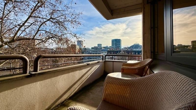 furnished balcony, 2 chairs, table, railings, view of cityscape