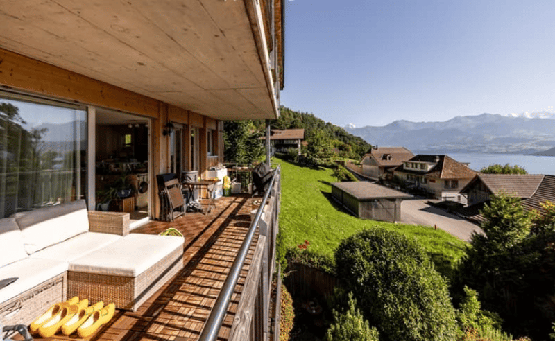 house on hillside, balcony, outdoor seating, lake view, mountains