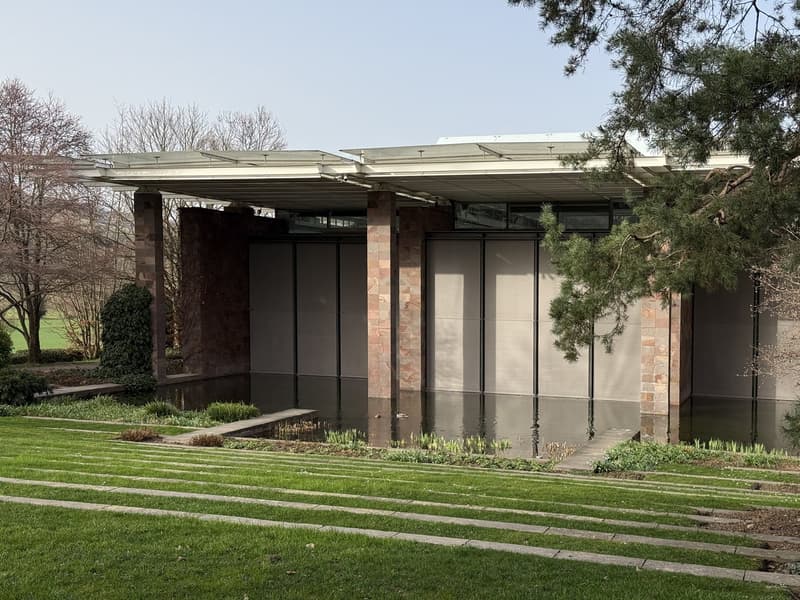modern design building, brick pillars, reflective pool in front, green lawn, trees, wide open area