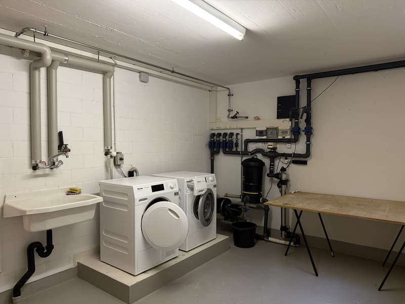 Laundry room with 2 washing machines, a sink, and a table