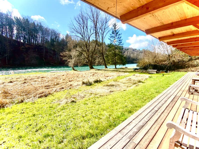 Wooden porch, overlooking grassy area and river
