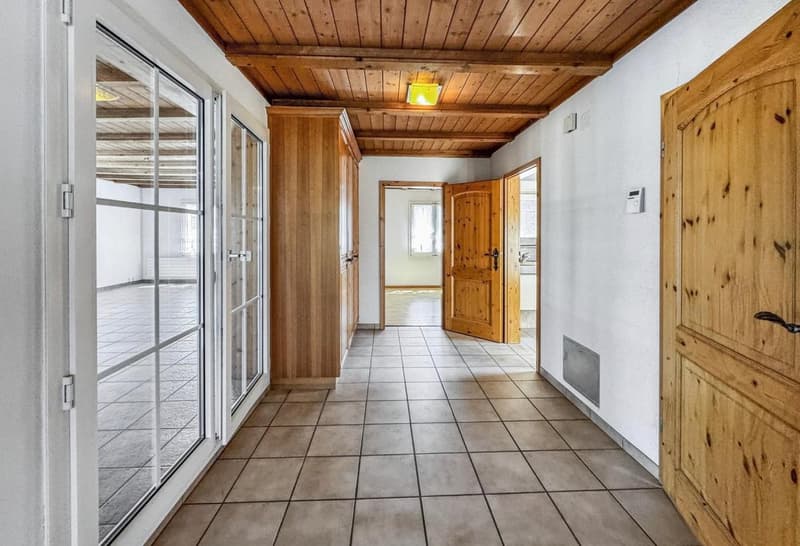 Empty hallway with tiled floor, wooden doors, glass doors, wooden ceiling, wooden cabinet