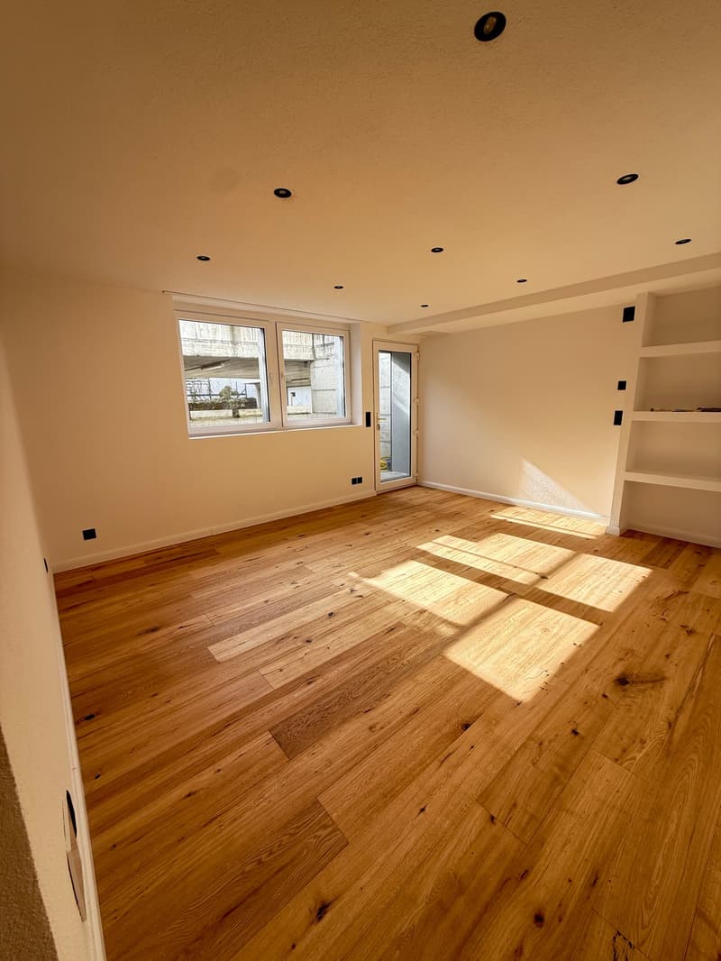 Empty room with hardwood floors, white walls, glass door, and windows.