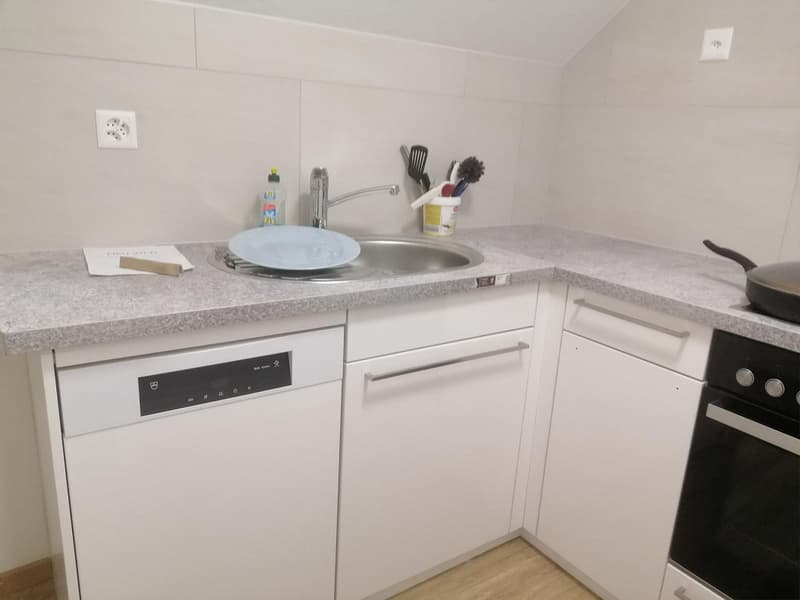 White cabinets, wooden floor, granite countertop, sink, dishwasher, oven, and other kitchen utensils