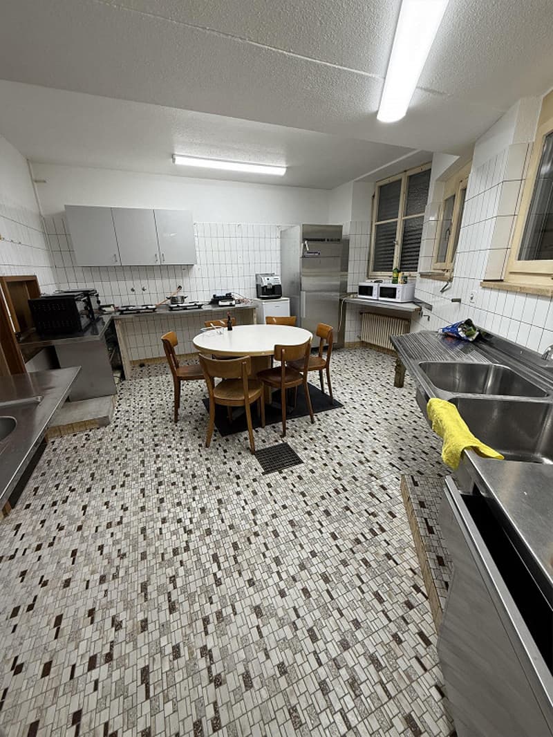 modern kitchen with round dining table and chairs, stainless steel countertops and cabinets, tiled floor, double sink, refrigerator, and appliances
