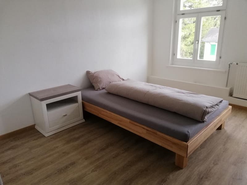 Single bed, nightstand, window, gray bedspread