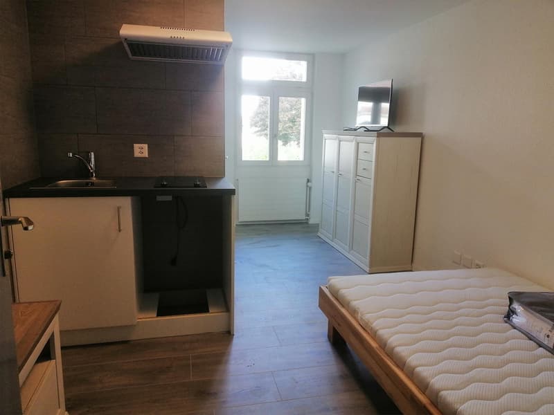 a small room, it has a sink, a bed, a cabinet and a TV.