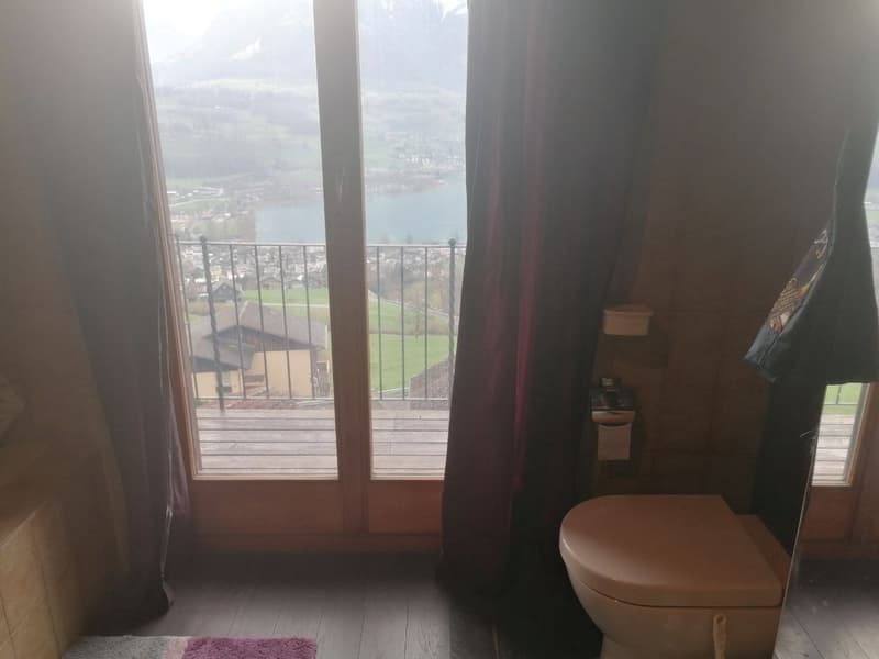 bathroom with toilet, large glass door, balcony, lake view