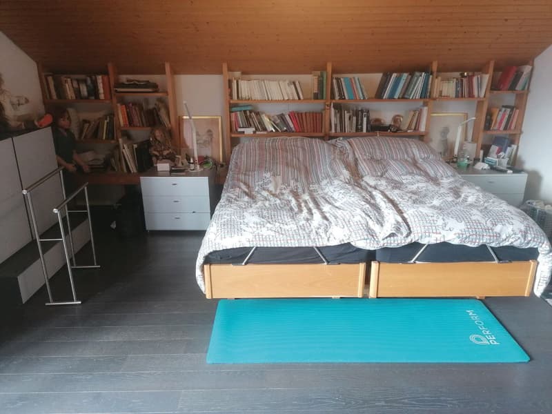 bedroom with bed, wooden shelves, desk, cabinets, yoga mat