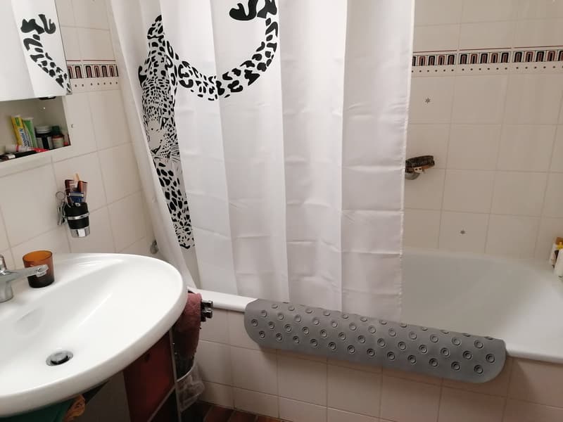 Bathroom with white tiles, white bathtub, white sink, white shower curtain, and a faucet