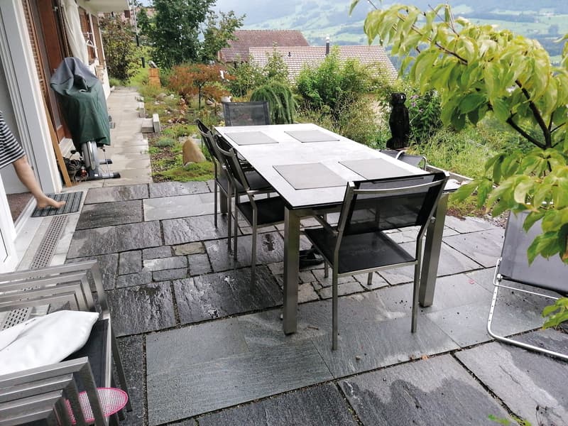Outdoor dining table with chairs, stone floor, garden, view of mountains