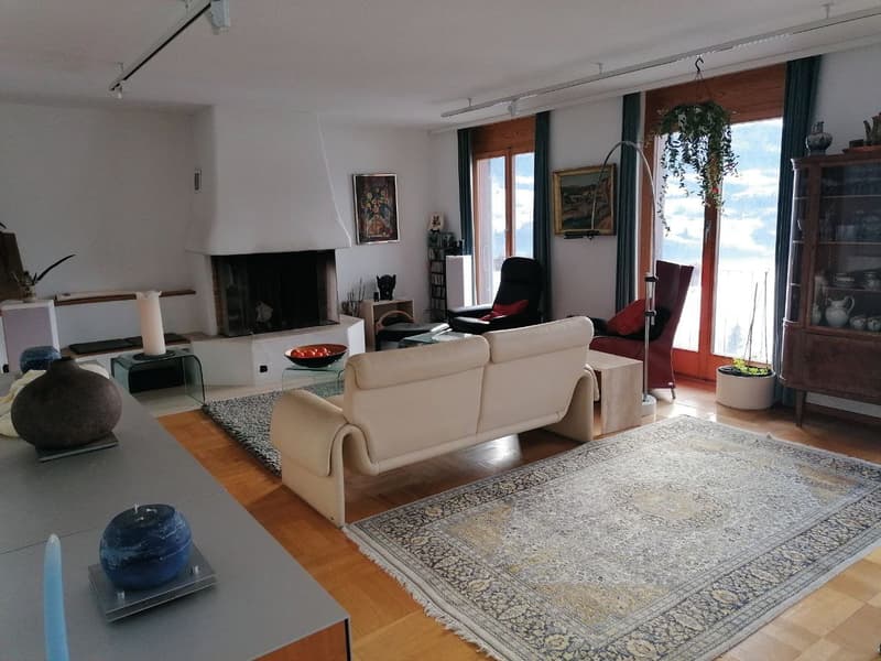 white walls, fireplace, beige sofa, wooden floor, large rug, glass table, glass coffee table, armchairs, wooden cabinet, potted plants