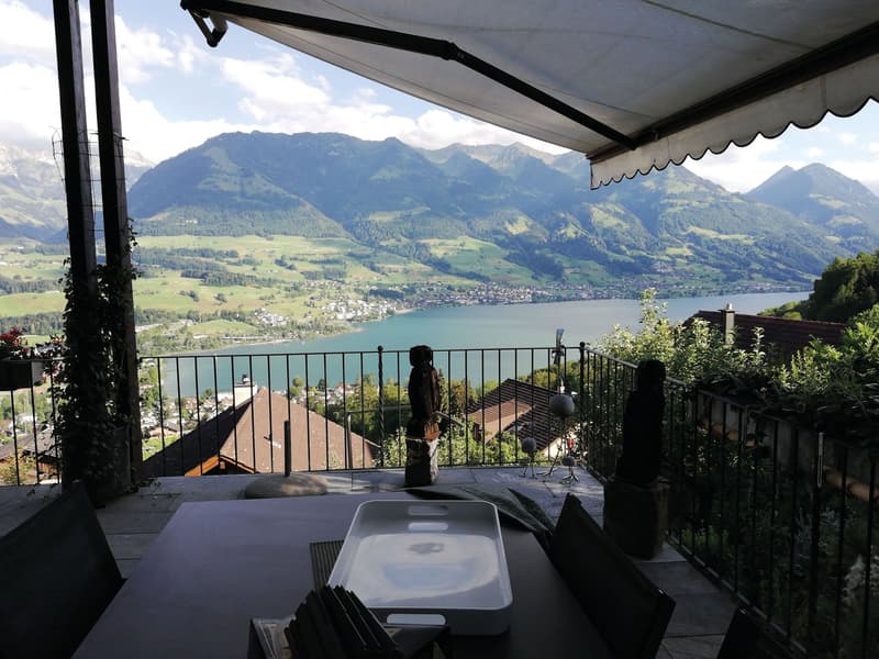 Balcony with table, chairs, and a view of the lake and mountains