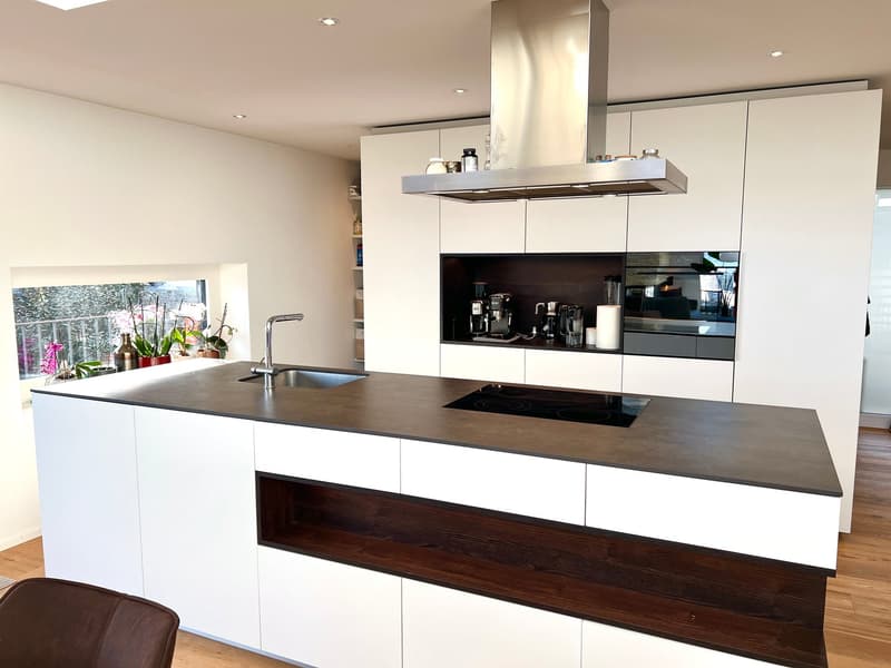 modern kitchen with white cabinets, black countertops, stainless steel appliances, island with sink and stove