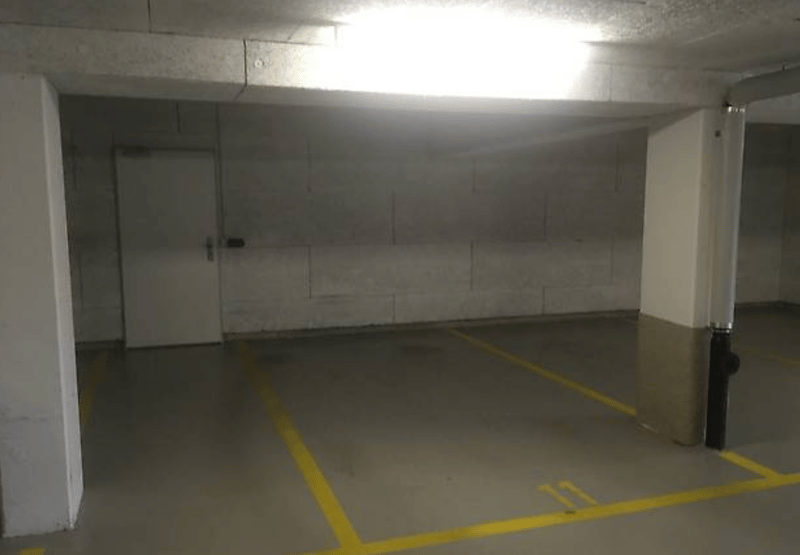 Empty parking lot with yellow lines, white walls, and a white door.